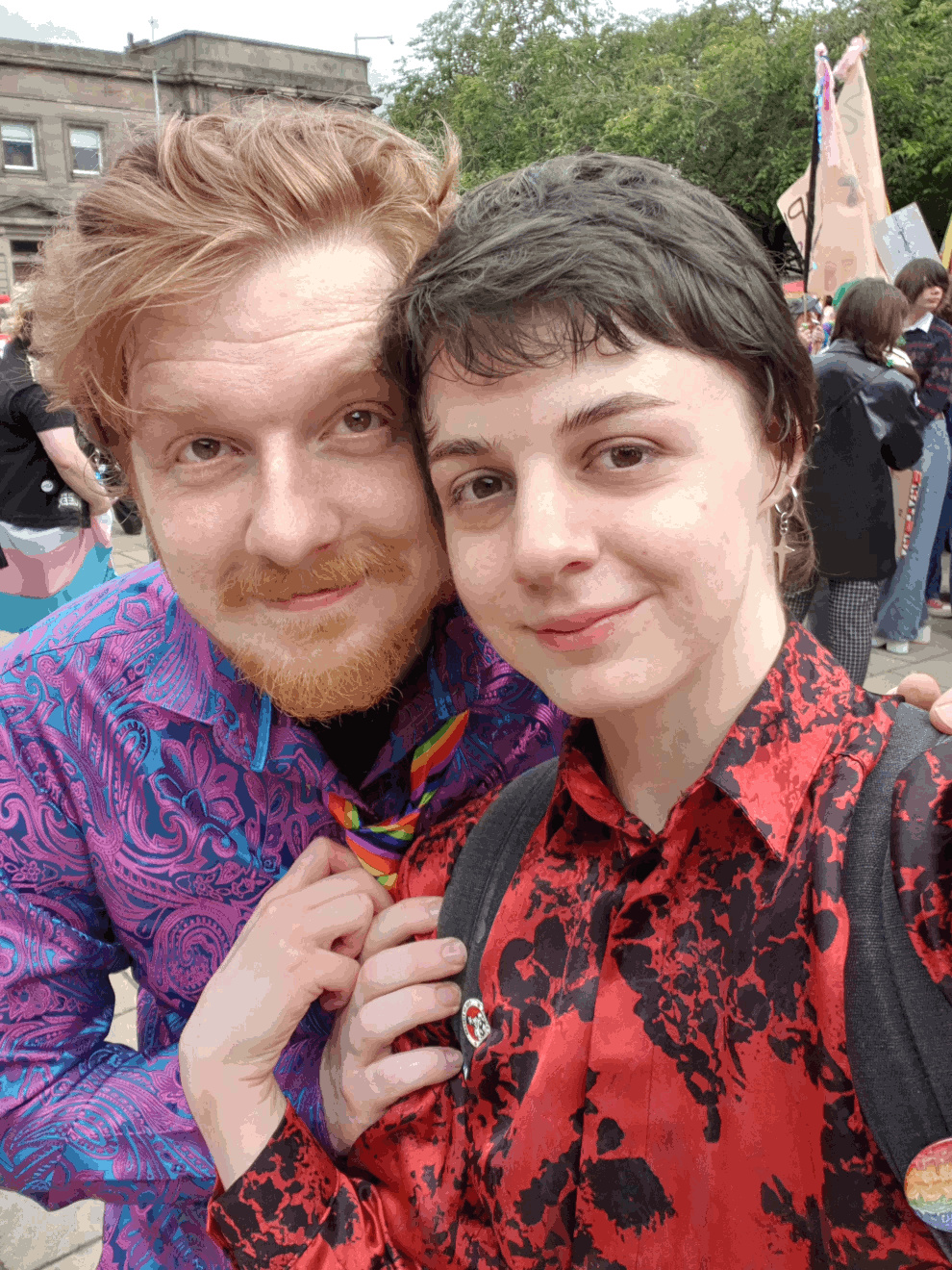 2 people; myself and my boyfriend, standing in front of a large group of LGBTQ+ people