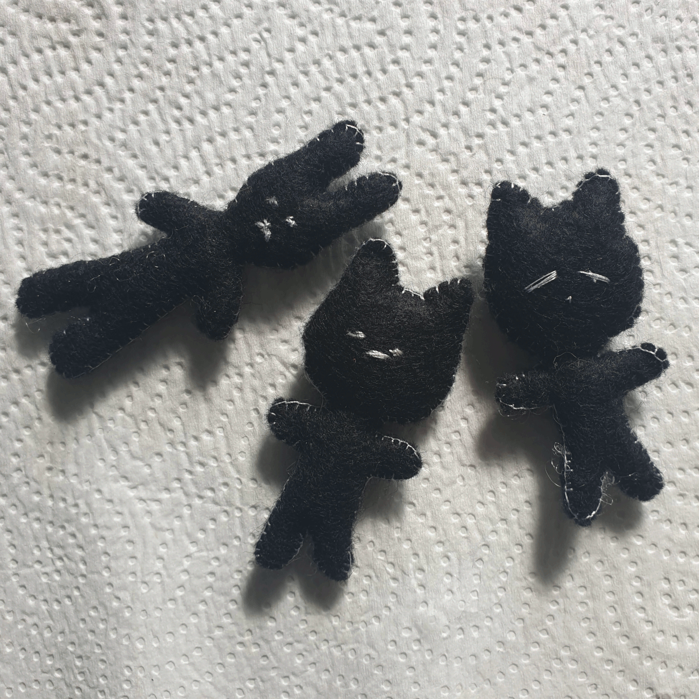 2 black felt cats with white stitching